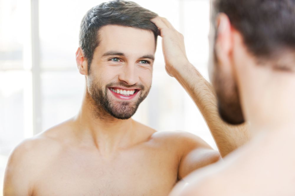 homem branco autoconfiante, sorrindo e olhando para o espelho